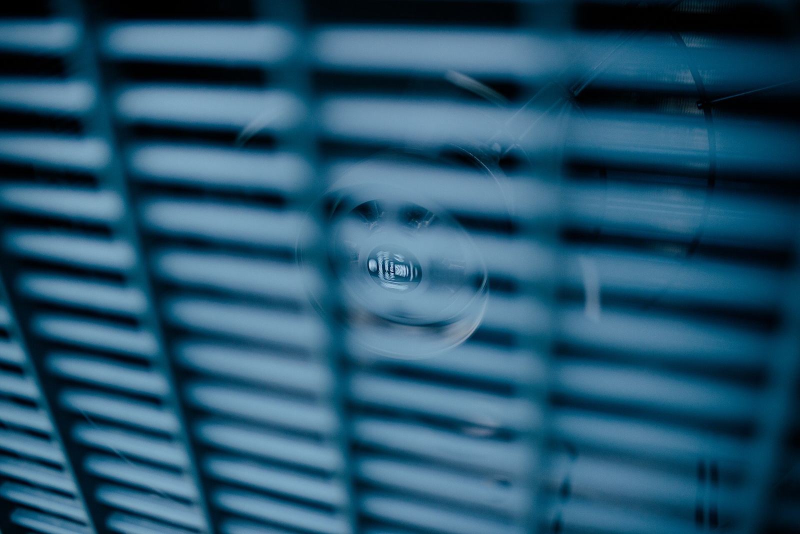 Close view of a residential heat pump fan through its protective grille